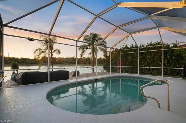 Swimming pool with a sunroom, glass enclosure, and a water view