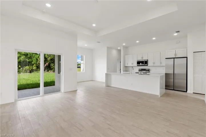 Unfurnished living room with a tray ceiling, light hardwood / wood-style floors, and sink