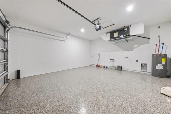 Garage featuring electric water heater and a garage door opener