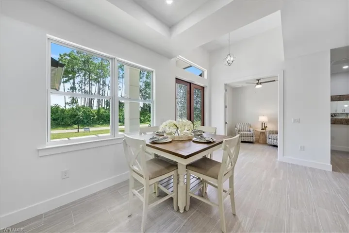 Dining room featuring a raised ceiling, light tile patterned flooring, ceiling fan, and french doors