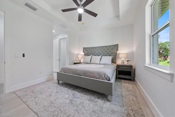 Bedroom with a tray ceiling, ceiling fan, and light hardwood / wood-style floors
