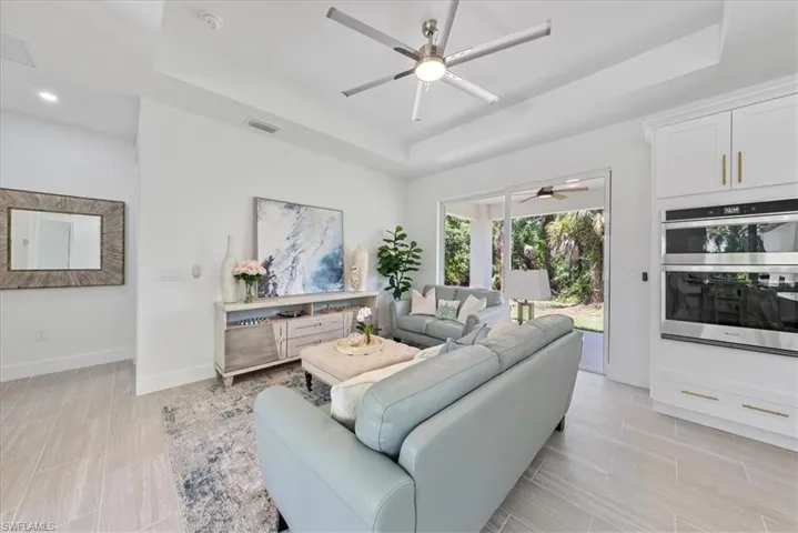 Living room featuring ceiling fan, light tile patterned floors, and a tray ceiling