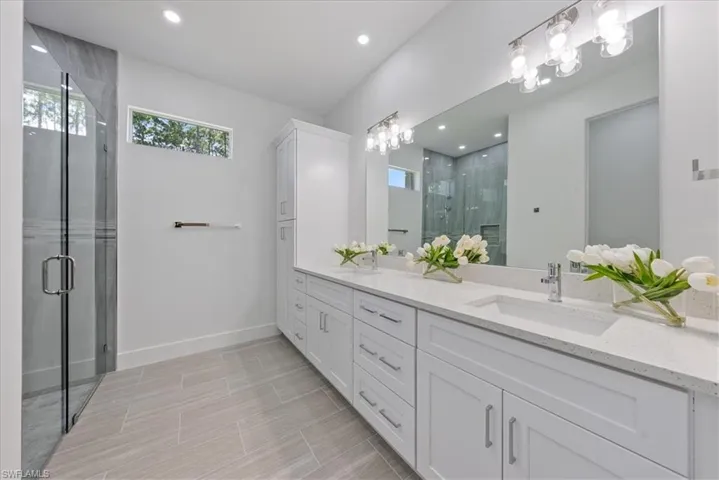 Bathroom featuring walk in shower, tile patterned floors, and double sink vanity