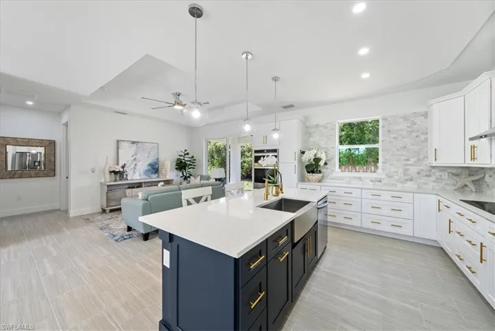 Kitchen with ceiling fan, a tray ceiling, tasteful backsplash, and plenty of natural light