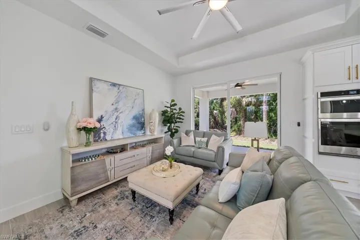 Living room with hardwood / wood-style flooring, ceiling fan, and a raised ceiling