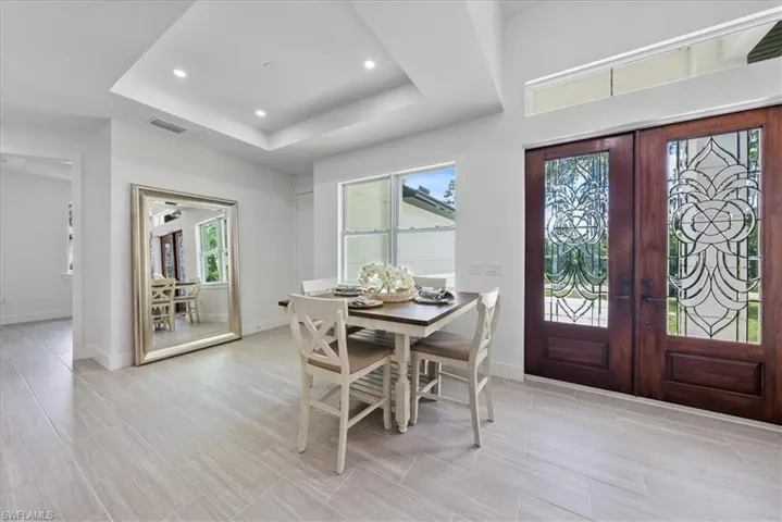 Dining room featuring a healthy amount of sunlight, a raised ceiling, french doors, and light tile patterned floors