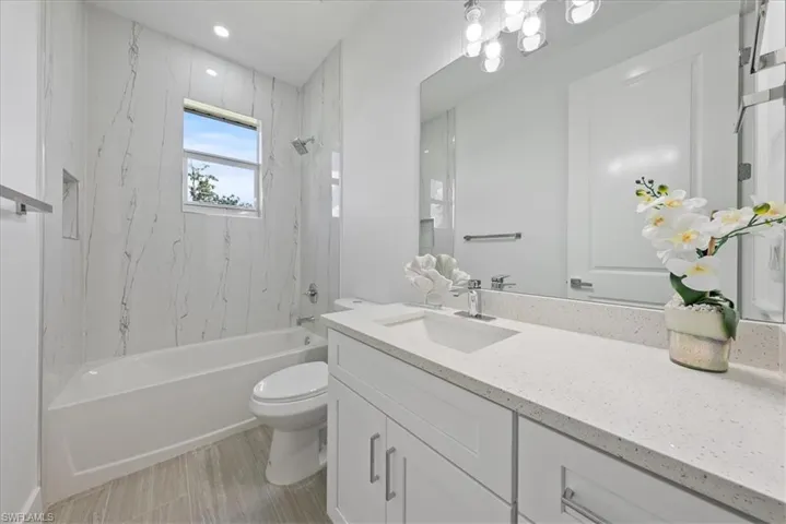 Full bathroom featuring tile patterned floors, vanity, tiled shower / bath combo, and toilet