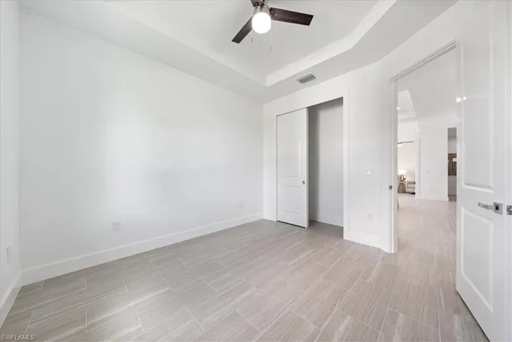 Unfurnished bedroom with a closet, ceiling fan, and a raised ceiling