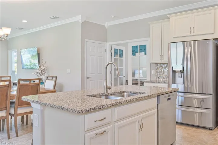 Kitchen featuring stainless steel appliances, an island with sink, sink, light stone countertops, and light tile patterned floors