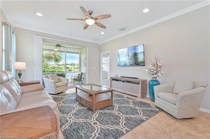 Tiled living room with ornamental molding and ceiling fan