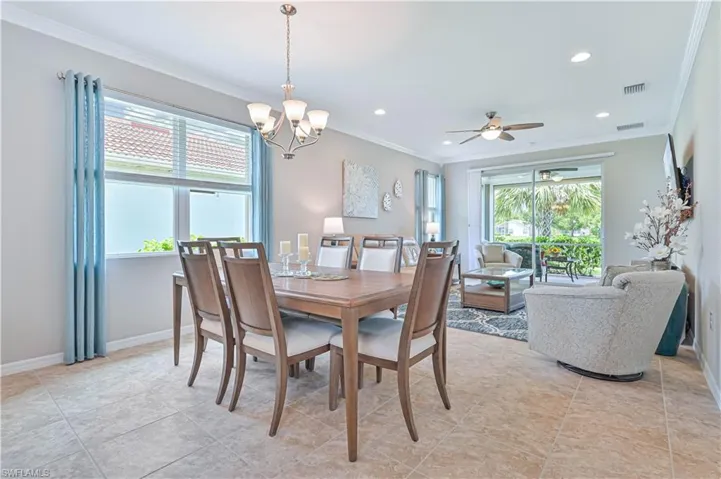 Tiled dining area featuring ceiling fan with notable chandelier and ornamental molding