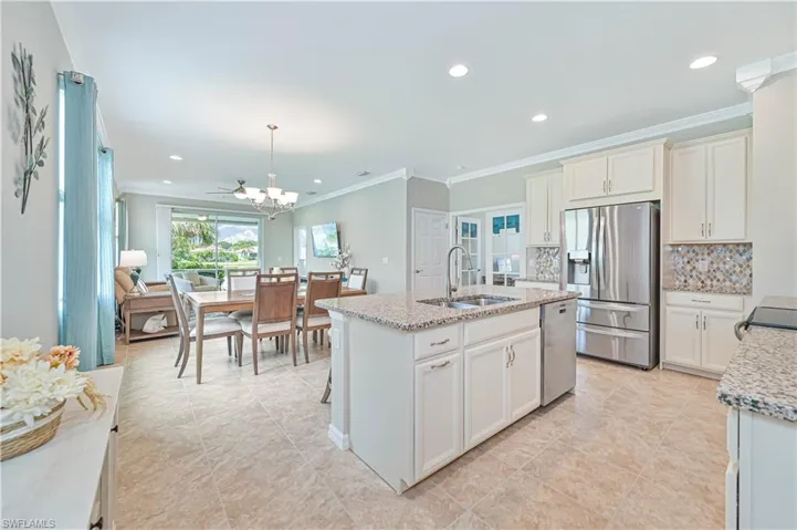 Kitchen featuring light tile patterned floors, light stone countertops, appliances with stainless steel finishes, pendant lighting, and sink