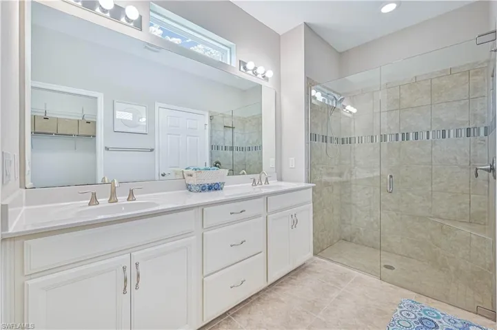 Bathroom featuring a shower with shower door, double sink vanity, and tile patterned flooring