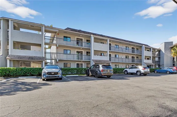 View of apartment building / complex featuring uncovered parking