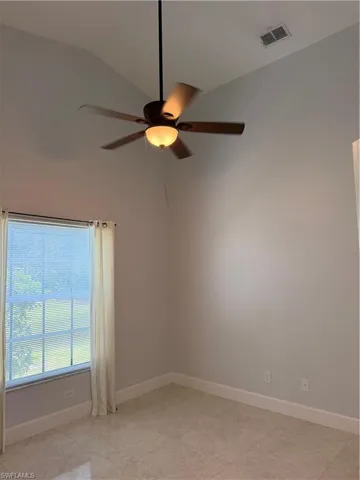 3rd Bedroom Vaulted ceiling featuring a ceiling fan with integrated lighting, tile flooring, window with blinds, and white baseboards