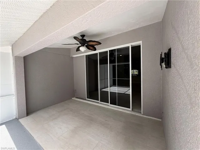 Covered patio featuring concrete flooring, a ceiling fan with light fixture, and sliding glass doors