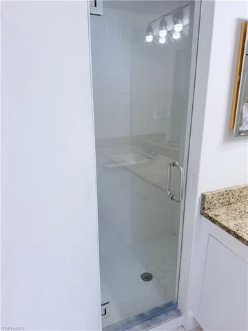 Glass-enclosed shower featuring white subway tile walls and hexagonal floor tiles
