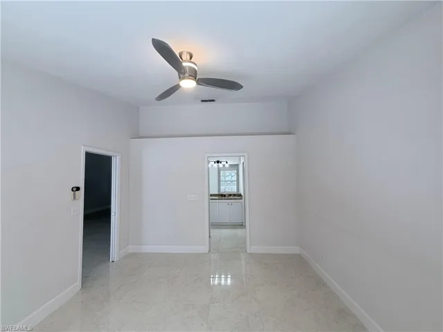Vaulted ceiling with decorative shelf, Neutral-toned walls complement the polished tile flooring throughout this interior space
