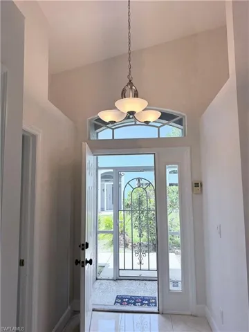 Foyer featuring vaulted ceilings, a polished tile floor, and a decorative pendant light fixture. Screened in area perfect when Fall and Winter arrrive!