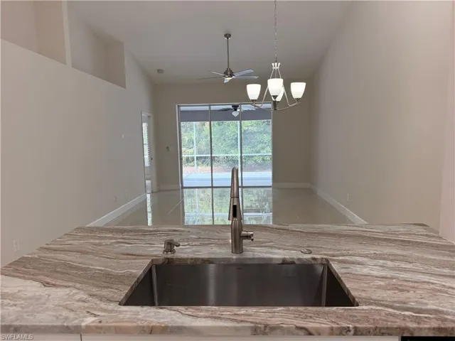 Kitchen island featuring a stainless steel undermount sink and a patterned stone countertop