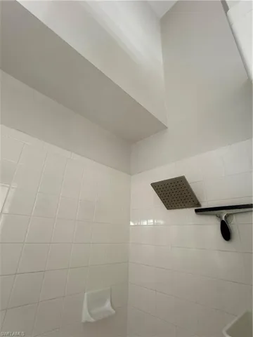 White tile shower enclosure featuring a square rain shower head and integrated soap dish