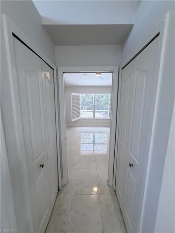 Hallway featuring tiled flooring, bi-fold closet doors, and light-toned walls 2 closets left and right