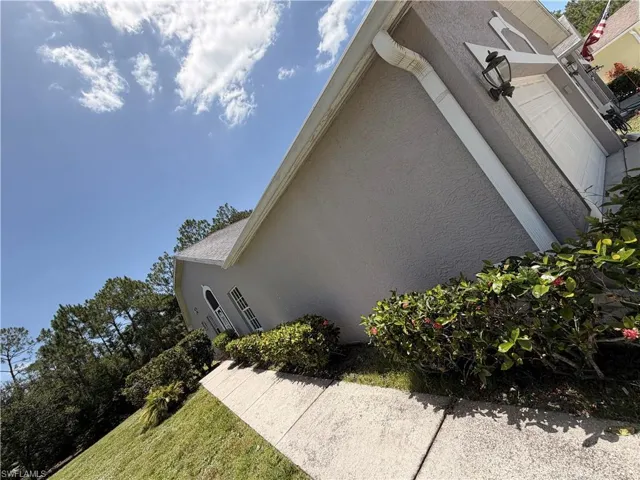 Stucco exterior with a peaked roofline, featuring a white garage door with decorative trim, an arched window, and exterior wall sconces