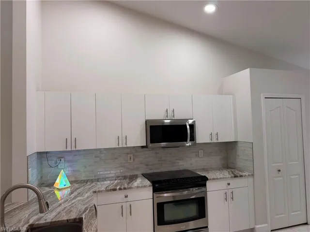 Modern kitchen featuring crisp white cabinetry, stainless steel appliances, and a mosaic tile backsplash