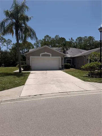 Single-story residence featuring a two-car garage with an arched accent above, a concrete driveway, and a shingle roof