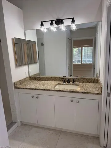 Bathroom granite countertop, integrated sink, and matte black faucet and light fixture.