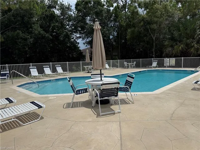 Rectangular swimming pool with blue tile accents, surrounded by a stamped concrete deck