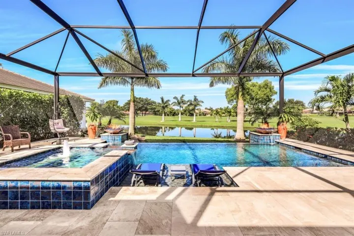 View of pool with a lanai, pool water feature, an in ground hot tub, a water view, and a patio
