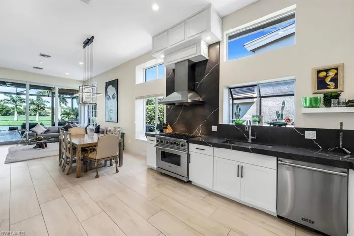 Kitchen featuring wall chimney exhaust hood, pendant lighting, a wealth of natural light, and stainless steel appliances