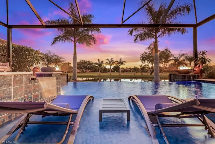 Pool at dusk featuring a water view and pool water feature