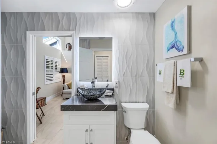 Bathroom featuring vanity, toilet, and tile walls