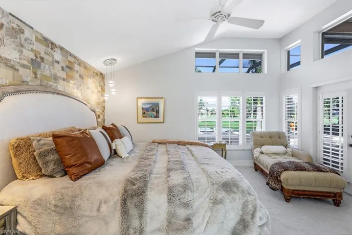 Carpeted bedroom featuring vaulted ceiling, multiple windows, and access to outside