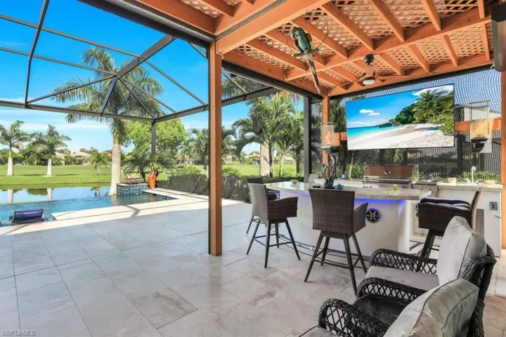 View of patio / terrace with a lanai, a water view, exterior kitchen, area for grilling, and ceiling fan