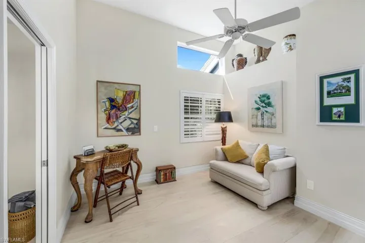 Sitting room with light wood-type flooring, a high ceiling, and ceiling fan
