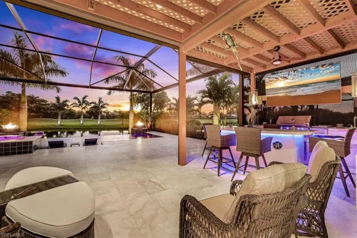 Patio terrace at dusk with a water view, grilling area, a pool, and a lanai
