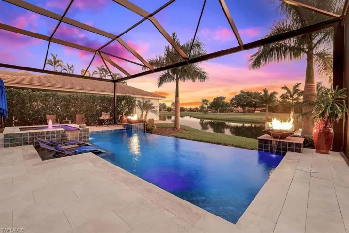 Pool at dusk with a water view, pool water feature, a patio area, and a lanai