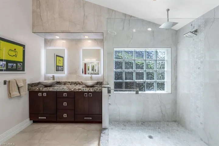 Bathroom featuring tiled shower and vanity