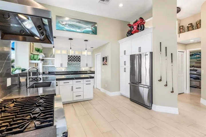 Kitchen with high end fridge, decorative light fixtures, sink, white cabinets, and light hardwood / wood-style floors