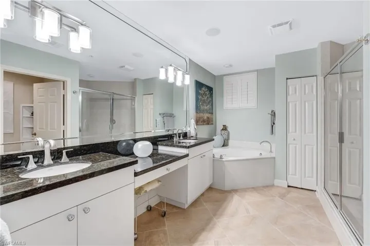 The primary bath showcases multi-tiered granite countertops, a separate soaking tub, and a walk-in shower—creating a soothing, spa-like experience.