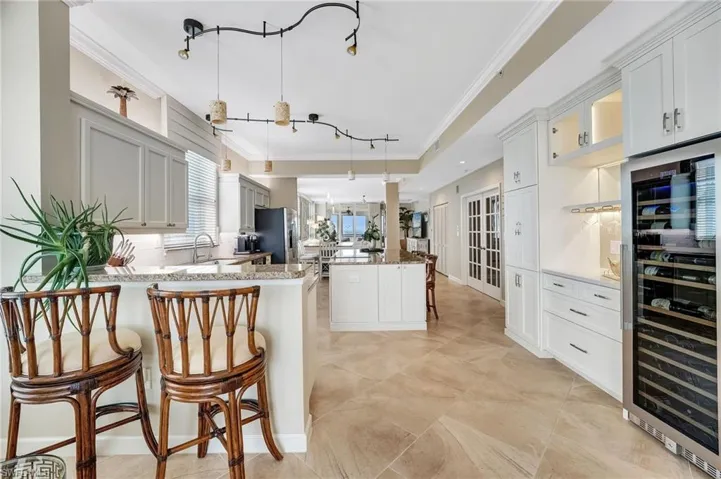 Directly across from the chef’s kitchen, a built-in bar shines with underlighting, glass-front cabinetry, ample storage, and an impressive 150-bottle wine cellar.
