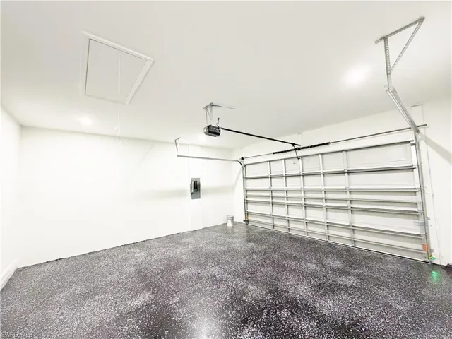 Spacious garage featuring a durable speckled epoxy floor, white walls, and a white ceiling