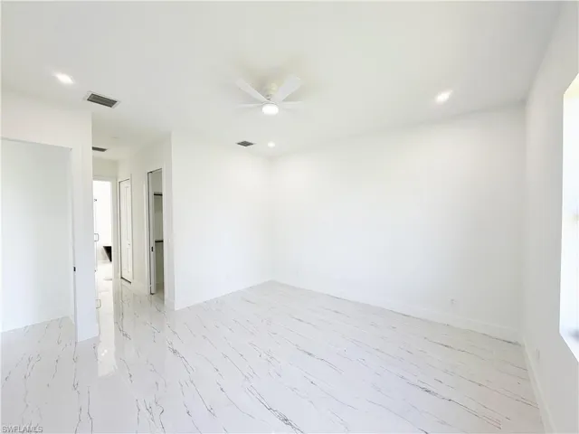 Spacious room featuring white walls and large-format porcelain tile flooring