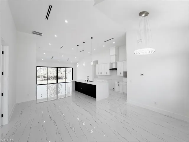 Spacious open-concept interior featuring large format marble-look tile flooring, high ceilings with recessed lighting, and expansive sliding glass doors