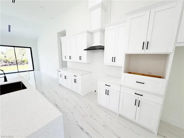 Modern kitchen featuring white shaker cabinetry with matte black hardware, white quartz countertops, and a full-height tile backsplash