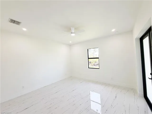 Bright interior space featuring large format marble-look tile flooring, white walls, and a contemporary ceiling fan