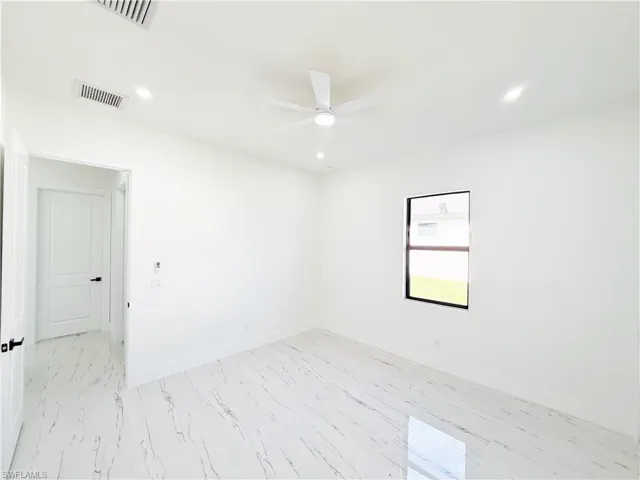 Bright interior room featuring polished marble-look tile flooring, white walls, and a modern ceiling fan